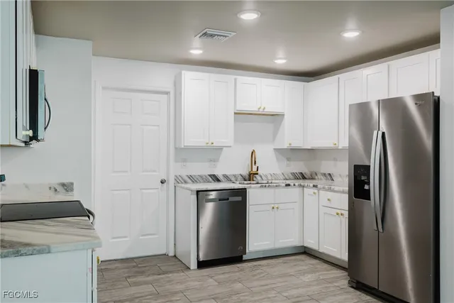 a kitchen with stainless steel appliances granite countertop a refrigerator a stove a sink and a microwave