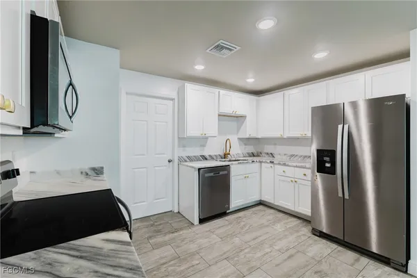 a kitchen with stainless steel appliances granite countertop a refrigerator and a stove top oven