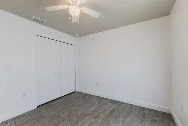 a view of an empty room with chandelier fan