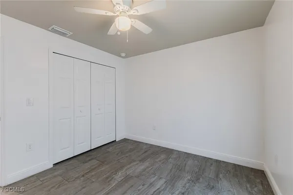 an empty room with wooden floor and fan