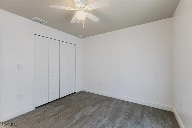 an empty room with wooden floor and fan