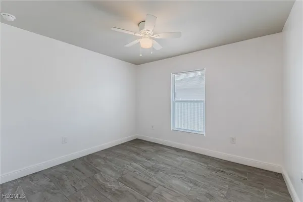 an empty room with wooden floor and fan