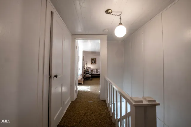 a view of a hallway with wooden floor and a bathroom