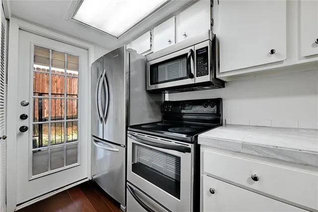 a kitchen with stainless steel appliances white cabinets and a stove top oven