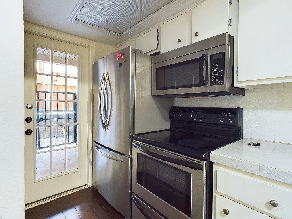 2104 Cullen Avenue, Unit 4117 Austin, TX 78757 - Photo 8 of 36 a kitchen with granite countertop cabinets stainless steel appliances and wooden floor