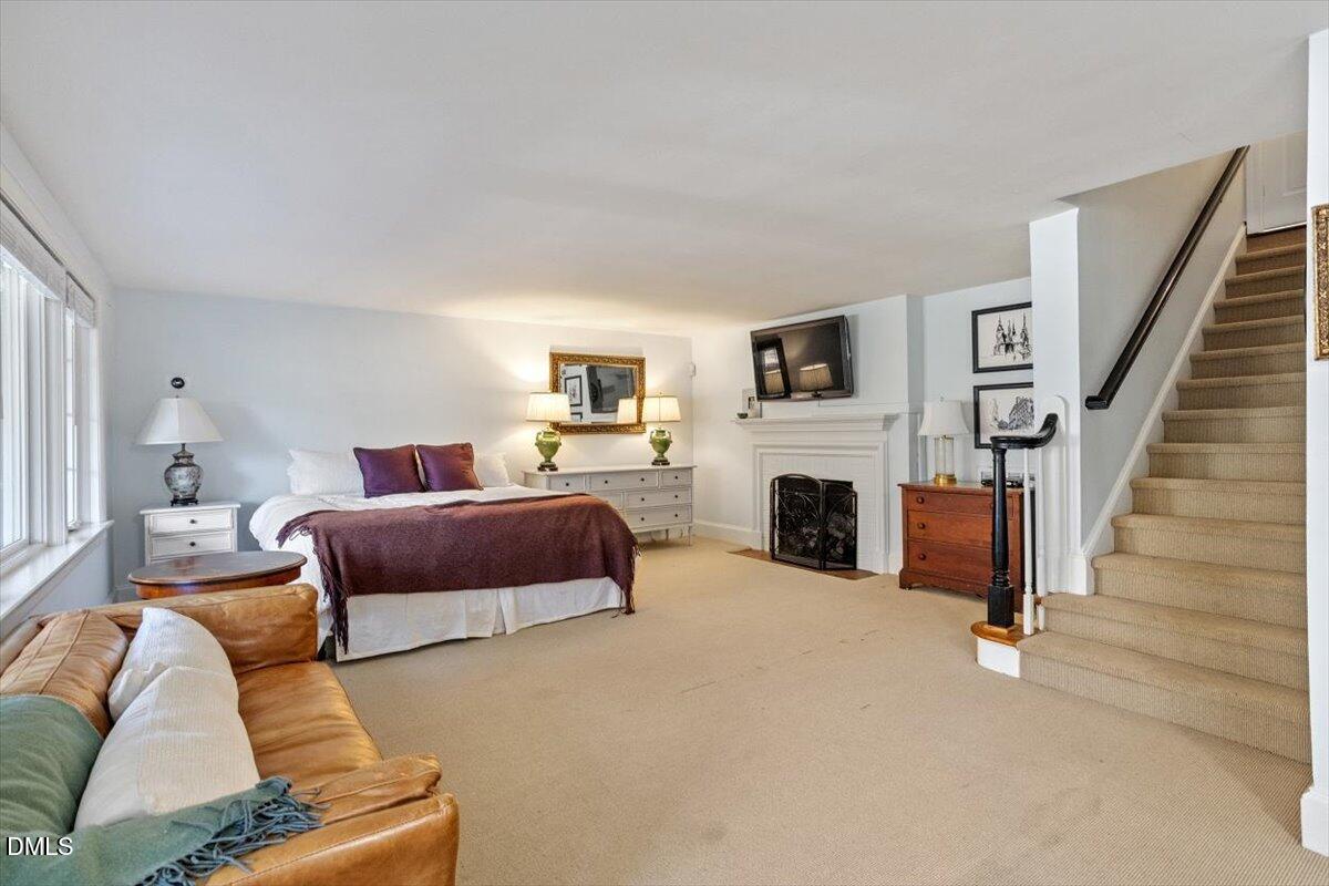 2416 East Lake Drive Raleigh, NC 27609 - Photo 33 of 42 a bedroom with furniture a fireplace and a flat screen tv