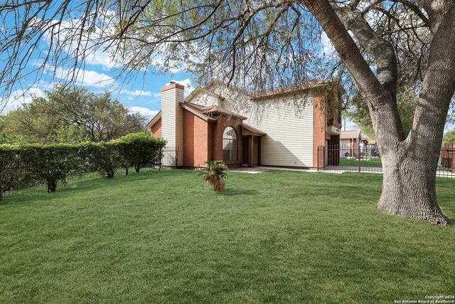a view of a white house with a big yard and large trees