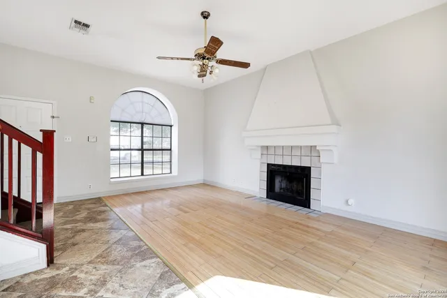 an empty room with windows fireplace and wooden floor