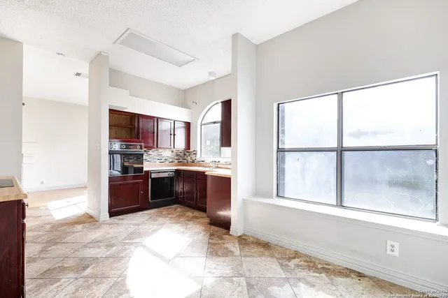 a large kitchen with a window and stainless steel appliances