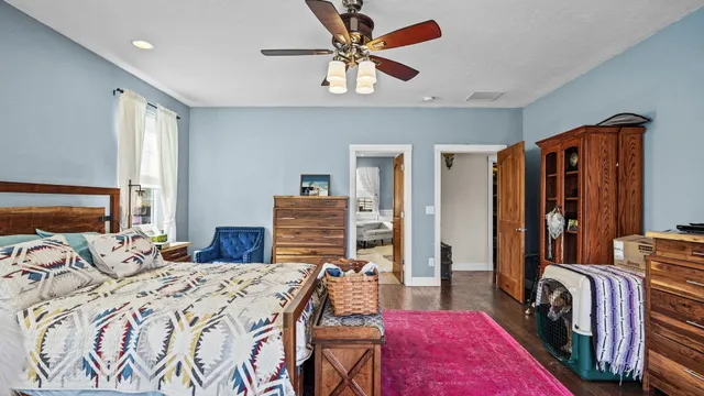 a bedroom with a bed a dresser and a chandelier