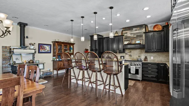 a kitchen with stainless steel appliances kitchen island granite countertop a table chairs refrigerator and microwave