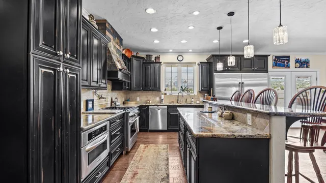 a kitchen with kitchen island granite countertop a sink stove and refrigerator