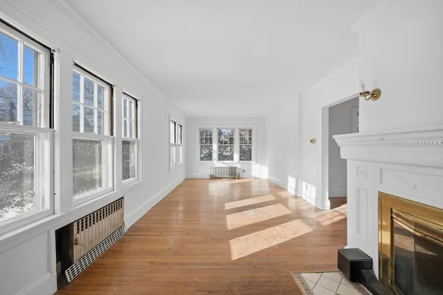 a view of an empty room with wooden floor and a fireplace