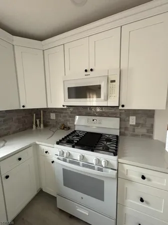 a kitchen with granite countertop white cabinets and white appliances