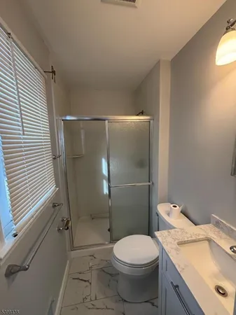 a bathroom with a granite countertop toilet and a shower