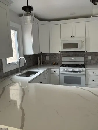 a kitchen with granite countertop a sink a stove and cabinets