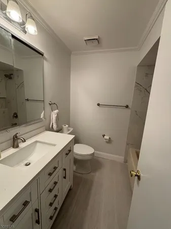 a bathroom with a granite countertop sink a toilet and shower