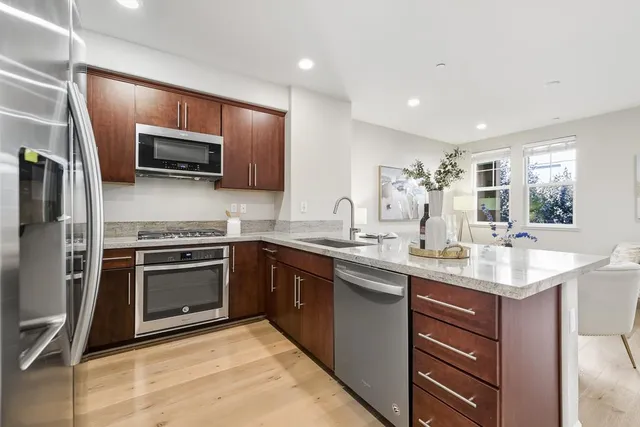 a kitchen with stainless steel appliances granite countertop a sink stove microwave and refrigerator