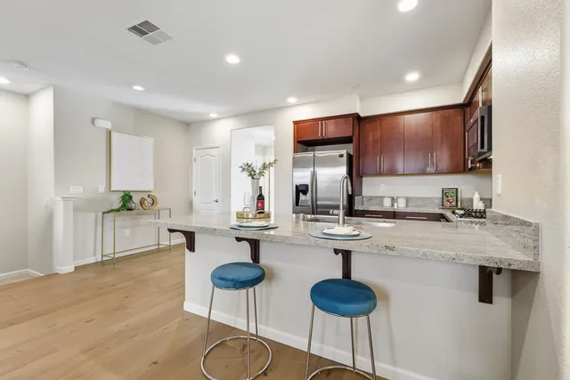 a kitchen with stainless steel appliances granite countertop a sink a stove and chairs with wooden floor