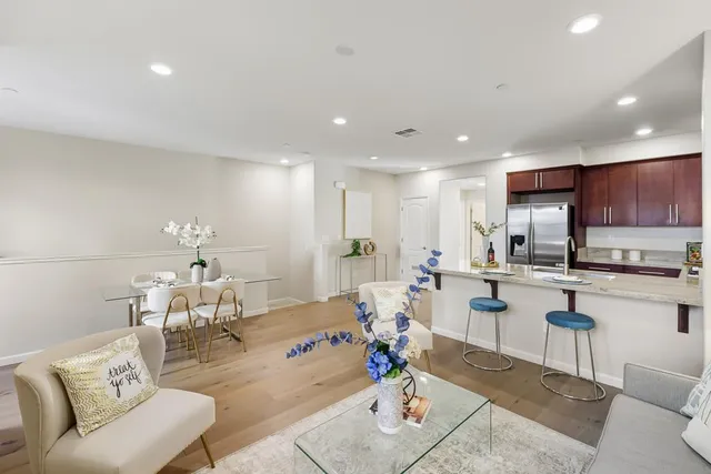 a living room with stainless steel appliances furniture a rug and a kitchen view