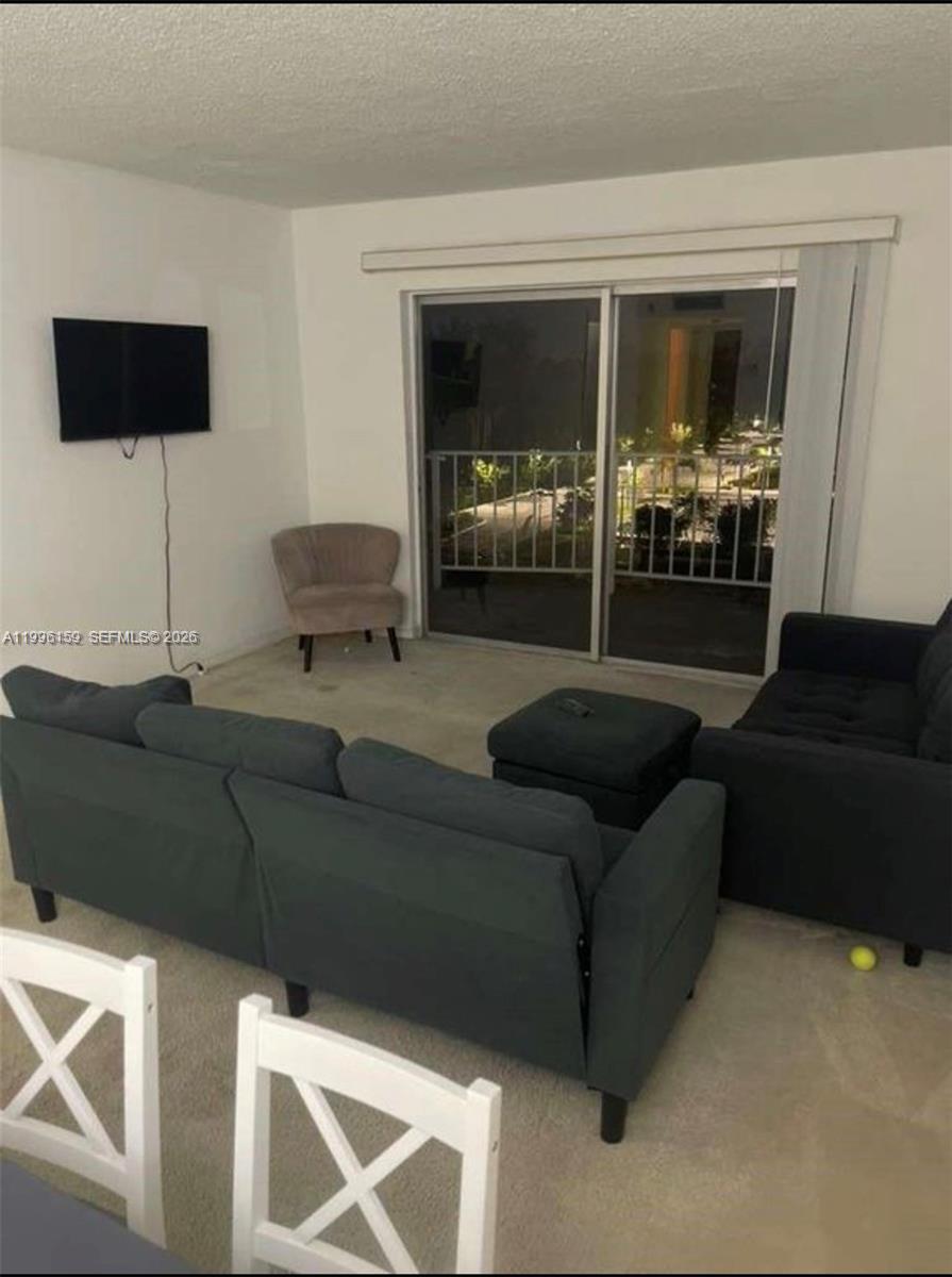 496 Northwest 165th Street, Unit D611 Miami, FL 33169 - Photo 8 of 8 a living room with furniture and a flat screen tv