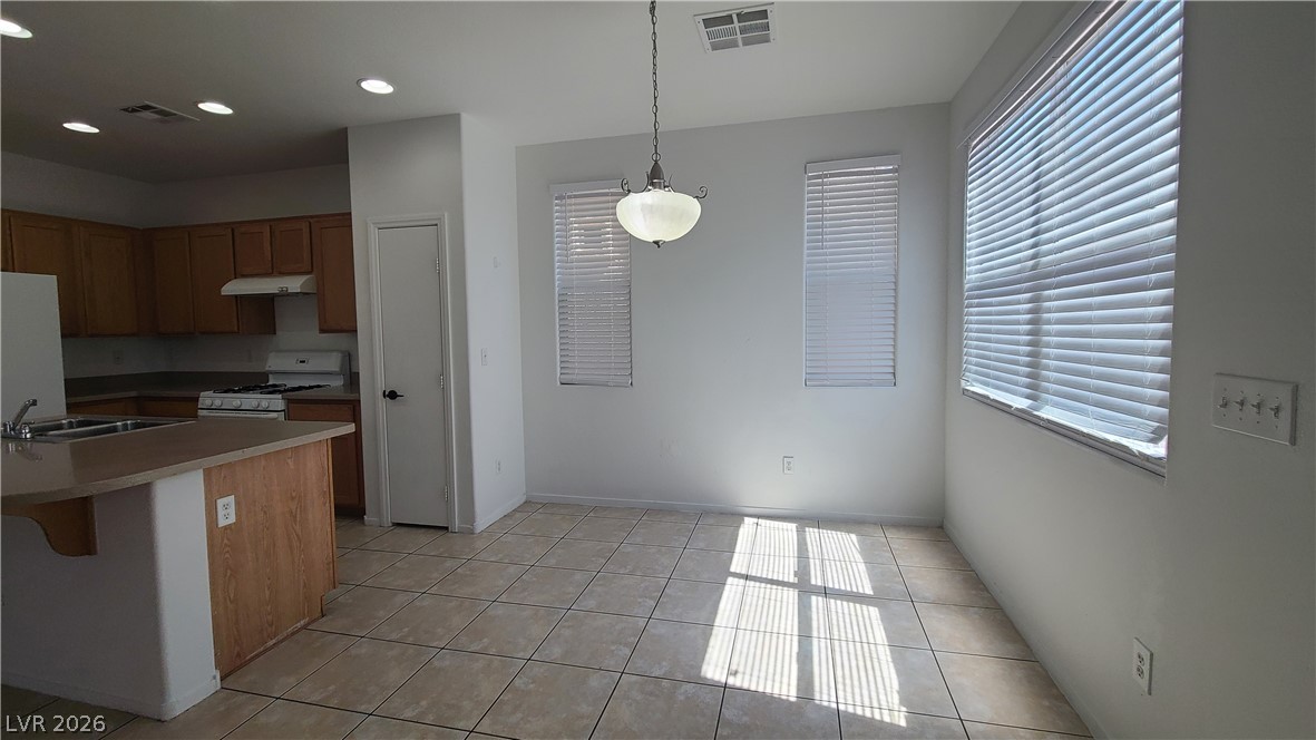 8944 Rutherford Grove Street Las Vegas, NV 89148 - Photo 6 of 35 A well-lit dining area featuring a classic chandelier and durable tile flooring.