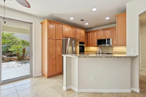 a kitchen with stainless steel appliances granite countertop a refrigerator and a stove top oven