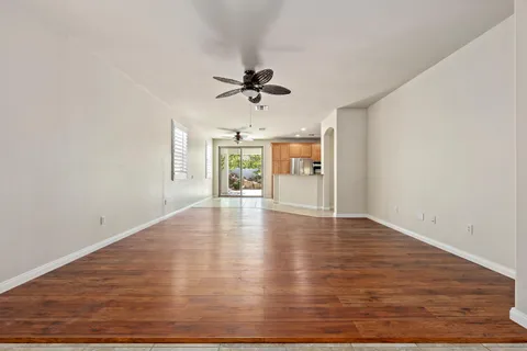 an empty room with wooden floor ceiling fan and windows