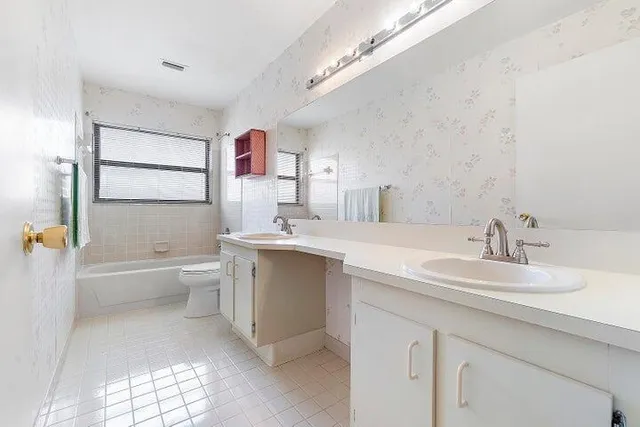 a bathroom with a double vanity sink mirror bathtub and toilet