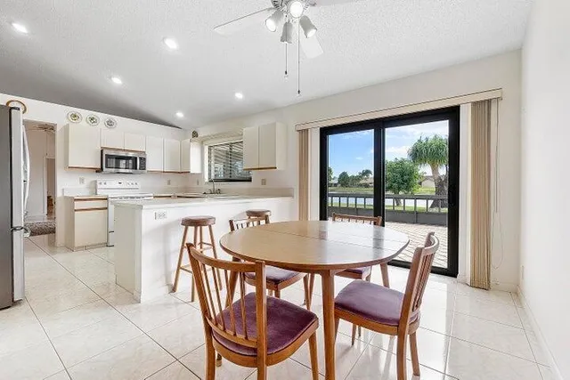 a kitchen with stainless steel appliances granite countertop a stove a refrigerator a kitchen island a table and chairs