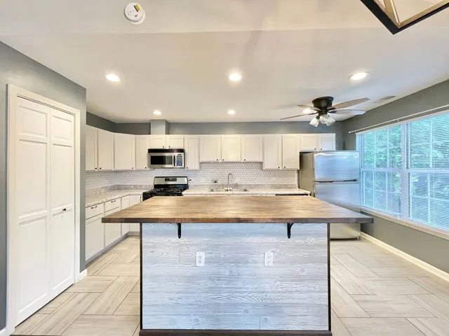 a room with kitchen island stainless steel appliances wooden floor and living room view