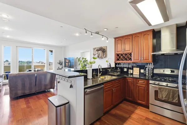a kitchen with stainless steel appliances granite countertop a stove a sink dishwasher and a microwave oven with cabinets