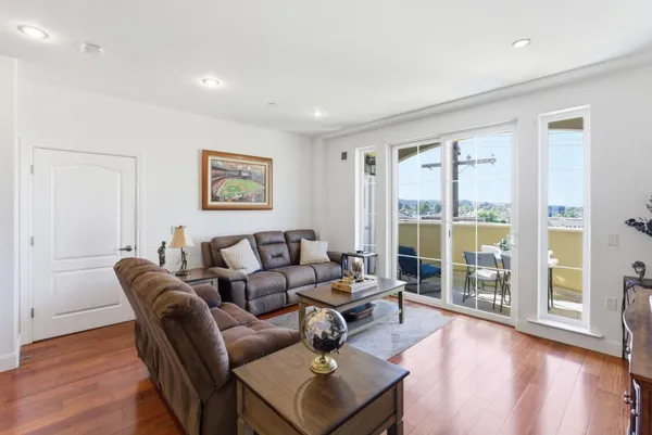 a living room with furniture large windows and wooden floor