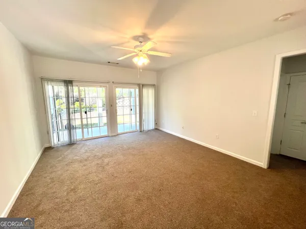 a view of an empty room with chandelier fan and fire place