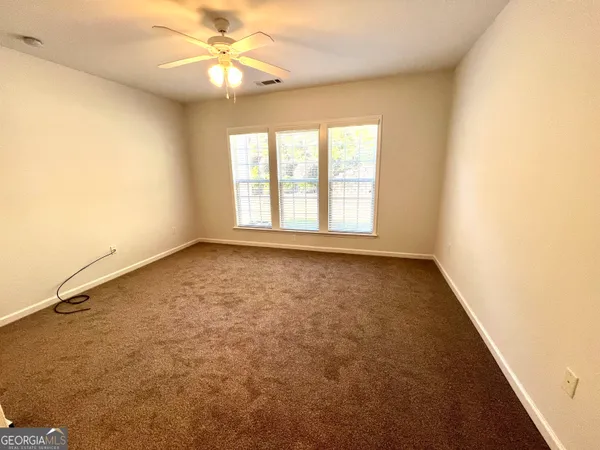 an empty room with a window and a ceiling fan