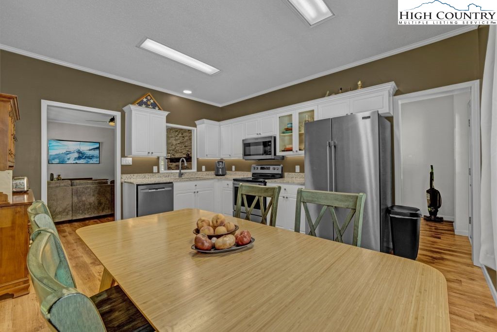 61 Snowbird Lane Linville, NC 28657 - Photo 4 of 19 a kitchen with a refrigerator a stove microwave oven with white cabinets and wooden floor