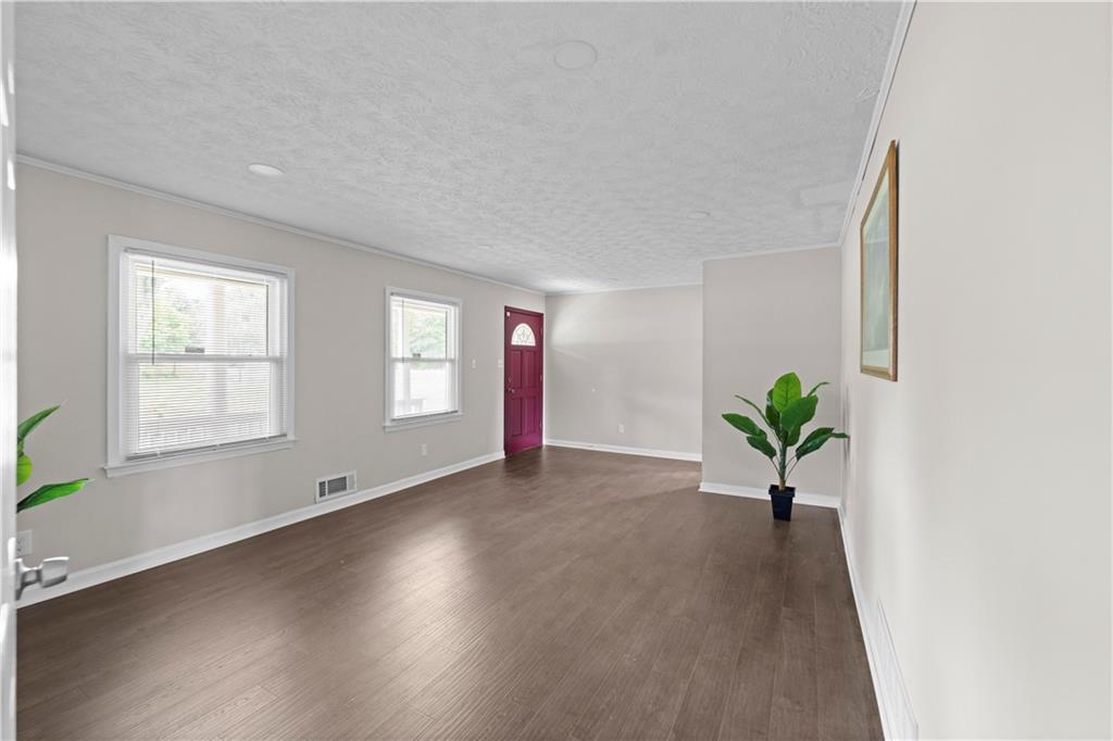 5245 Stonewall Tell Road Atlanta, GA 30349 - Photo 4 of 15 a view of an empty room with a window and wooden floor