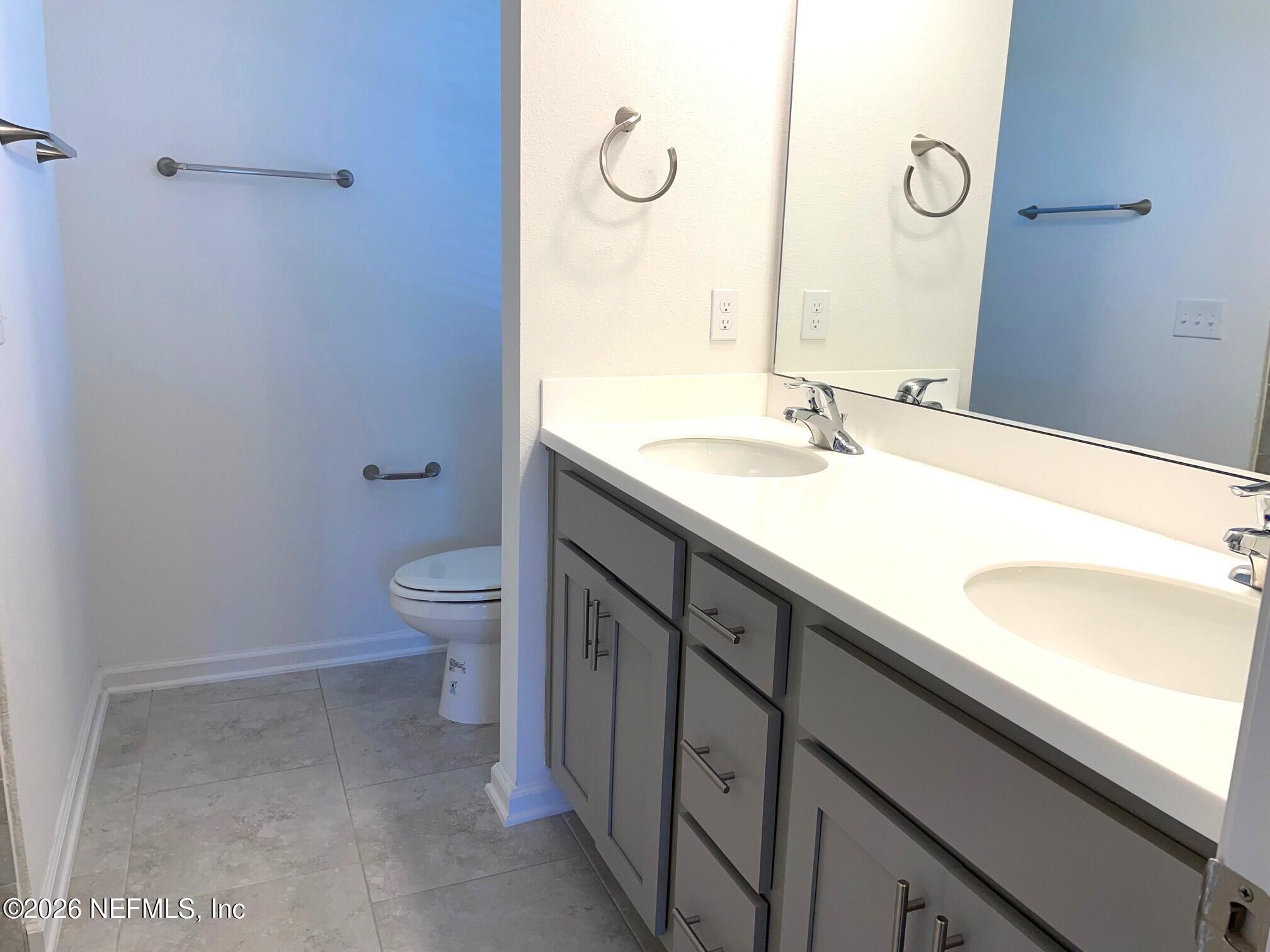 106 Ridge Lake Rd Street St. Augustine, FL 32086 - Photo 16 of 31 a bathroom with a granite countertop sink a toilet and a mirror