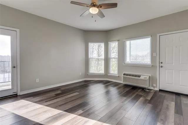 a view of an empty room with a window and wooden floor