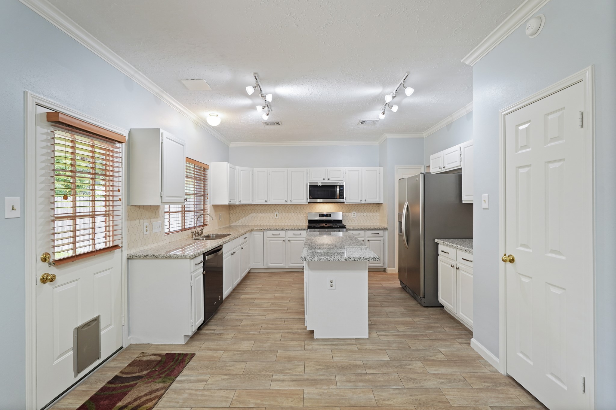 16215 Wemyss Bay Road Houston, TX 77095 - Photo 5 of 44 a kitchen with stainless steel appliances a refrigerator a sink dishwasher a stove and white cabinets with wooden floor