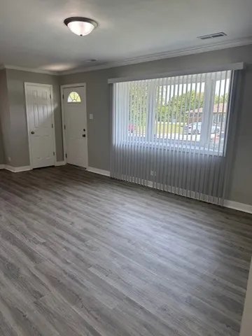 an empty room with wooden floor and windows