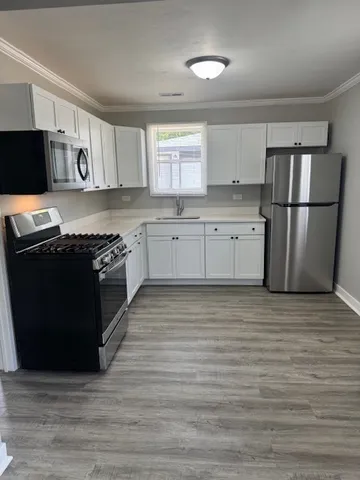 a kitchen with stainless steel appliances granite countertop a stove a sink dishwasher a refrigerator and a stove with wooden floor