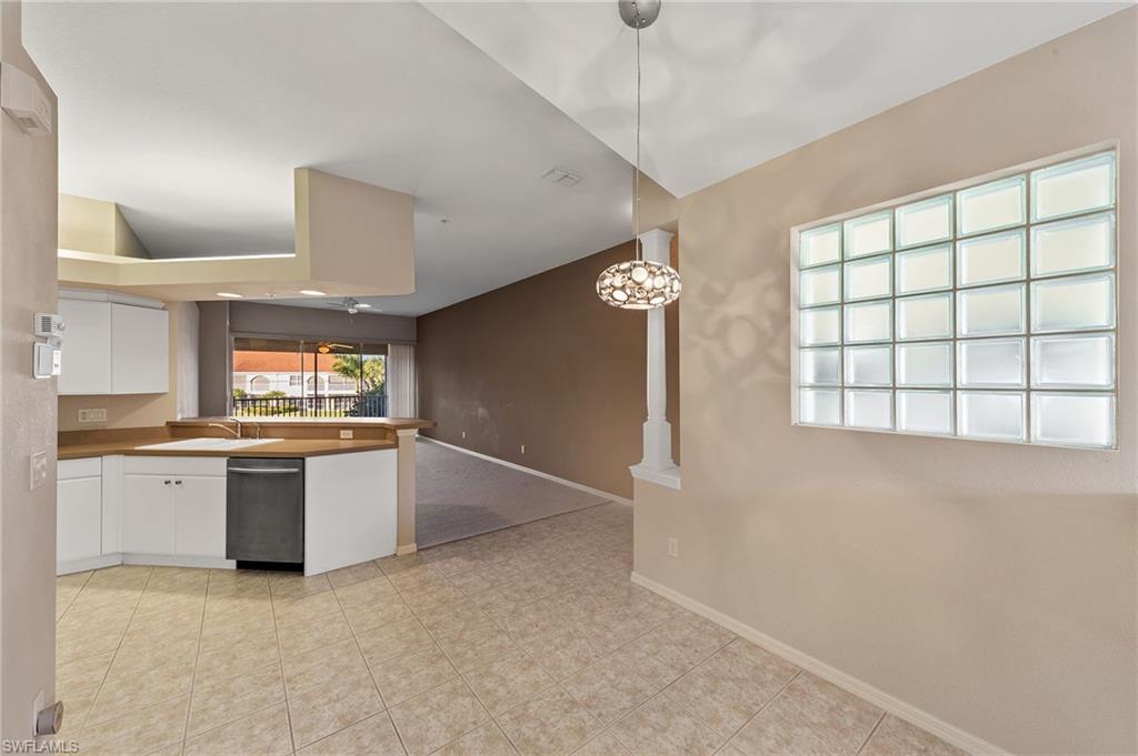 23810 Costa Del Sol Road, Unit 203 Estero, FL 34135 - Photo 11 of 48 Kitchen featuring white cabinets, hanging light fixtures, stainless steel dishwasher, open floor plan, and a peninsula