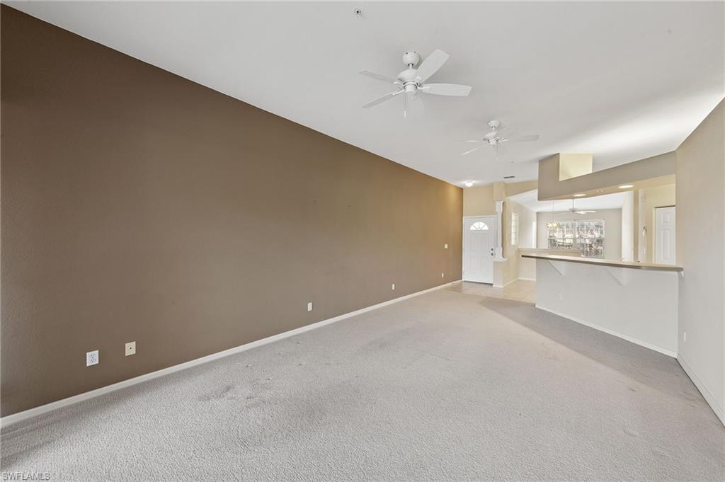 23810 Costa Del Sol Road, Unit 203 Estero, FL 34135 - Photo 14 of 48 Unfurnished living room featuring light carpet and ceiling fan