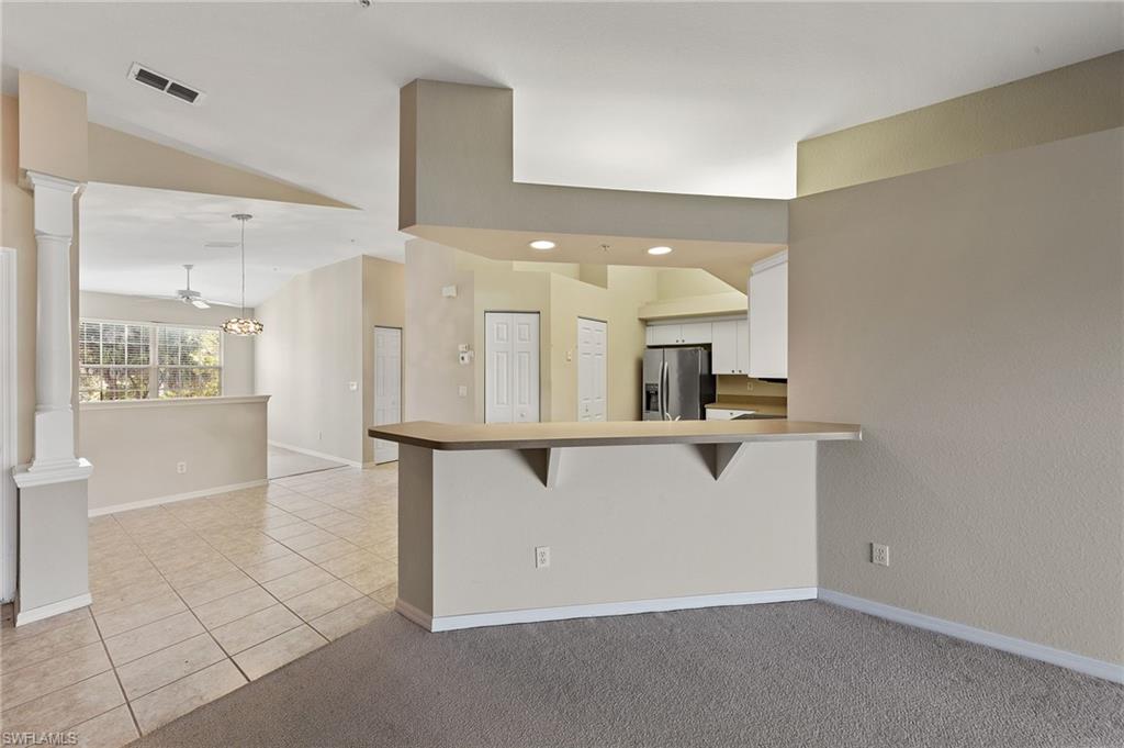 23810 Costa Del Sol Road, Unit 203 Estero, FL 34135 - Photo 5 of 48 Kitchen featuring a kitchen breakfast bar, light colored carpet, white cabinetry, stainless steel fridge with ice dispenser, and a peninsula