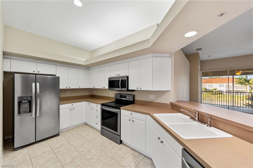 23810 Costa Del Sol Road, Unit 203 Estero, FL 34135 - Photo 8 of 48 Kitchen featuring appliances with stainless steel finishes, recessed lighting, white cabinetry, a raised ceiling, and light tile patterned flooring