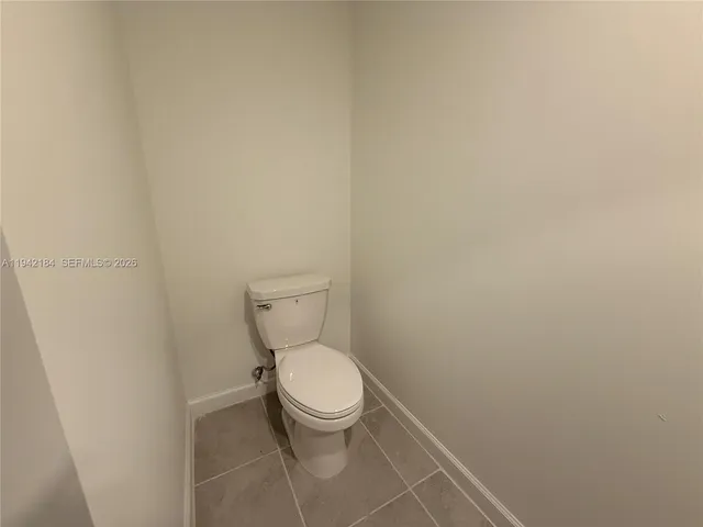 a white toilet sitting next to a white wall