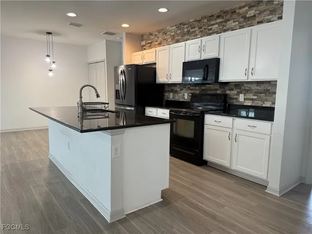 a kitchen with granite countertop a sink cabinets and wooden floor