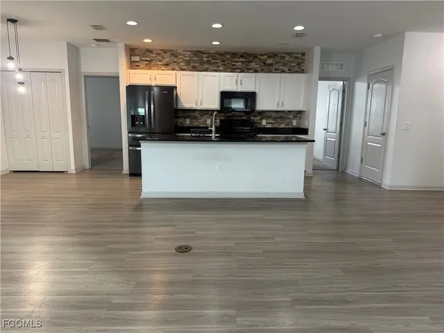 a view of kitchen with stainless steel appliances wooden floor and large window
