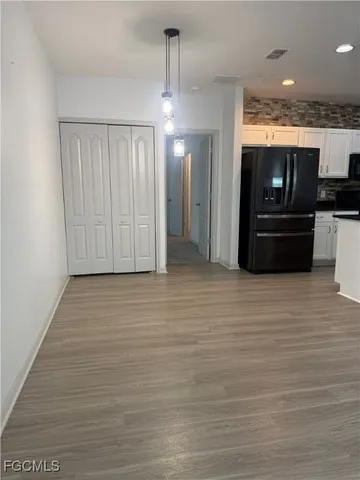 an empty room with a chandelier fan and windows
